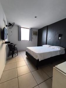 a bedroom with a bed and a desk and a television at Stratus Vila Hotel in Volta Redonda