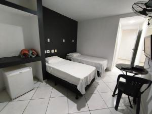 a bedroom with two beds and a table and a chair at Stratus Vila Hotel in Volta Redonda +54 photos