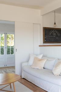 a white living room with a white couch and a table at The Vintage Cottage in Oneroa +9 photos