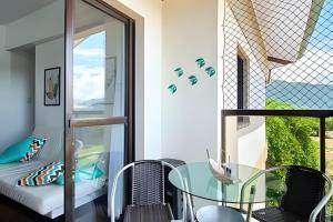 a room with a glass table and chairs and a bed at CHARMOSO seu apto a apenas 300 mts da rua mais turistica de ubatuba in Ubatuba