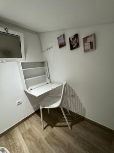 ein weißer Raum mit einem Stuhl und einem Fernseher an der Wand in der Unterkunft Malecón Do Azeite in Moura