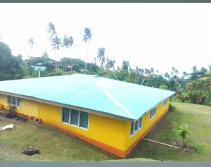 a yellow house with a blue roof at JayDees Homestay in Taveuni