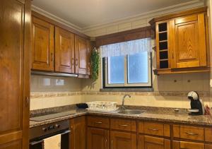 a kitchen with wooden cabinets and a sink and a window at Casa do Evaristo in Nabais