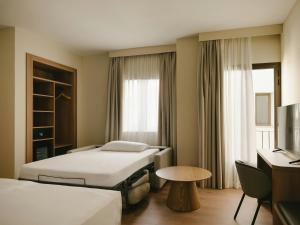 a hotel room with two beds and a desk at Sercotel Toledo Imperial in Toledo
