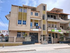a large building with a fence in front of it at Apartamento T2-Dunas Centro in Tarrafal