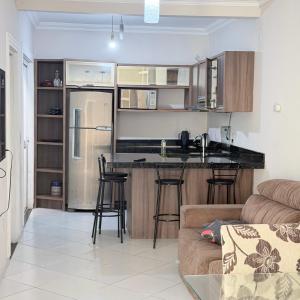a kitchen and living room with a counter and a refrigerator at Casa de 2 QUARTOS COM PISCINA in Balneário Camboriú