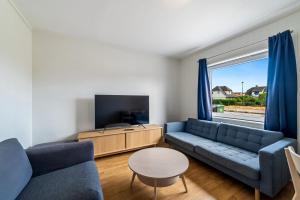a living room with a blue couch and a tv at Oddernesveien 7 in Kristiansand