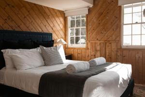 a bedroom with a large bed with wooden walls at White Shell Cottage - Woodfire & Beachfront in Falmouth