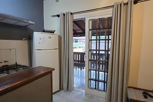 a kitchen with a refrigerator and a door to a balcony at Chalé Private c/ Vista e garagem in Ilhabela