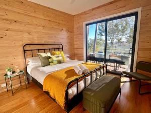 a bedroom with a bed and a large window at Hudsons Hideaway - Cosy Eco Cabin, Rainforest Walks in Dorrigo
