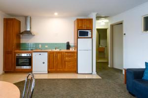 a kitchen with wooden cabinets and a white refrigerator at Waves on Banyan formerly Comfort Inn International in Warrnambool
