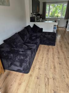 a black couch in a living room with a wooden floor at 78 Atlantic Reach in Newquay