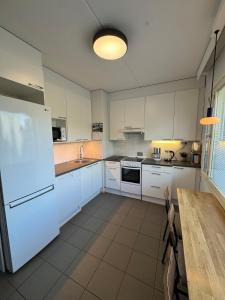 eine Küche mit weißen Schränken, einem Tisch und einem Kühlschrank in der Unterkunft Mon Koti in Turku