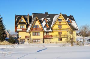 a large yellow house with a black roof at Dom Wypoczynkowy Skorusa in Białka Tatrzańska