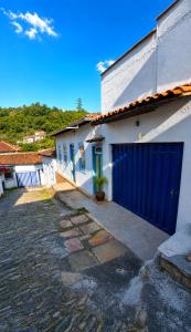 a garage with a blue door on a white building at Casa Completa No Centro Para Famílias e Grupos Até 9 Hospedes Com Garagem in Ouro Preto