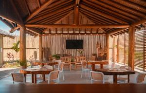 a pavilion with tables and chairs and a flat screen tv at Falésias Orybá in Corumbau