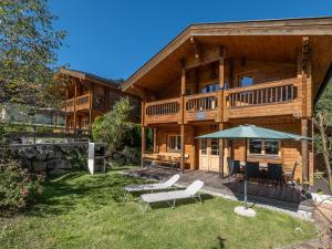 a large wooden house with a patio and an umbrella at Waldberg in Krimml