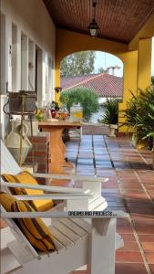 a porch with a table and a bench on a patio at Casas do Alpendre in Óbidos