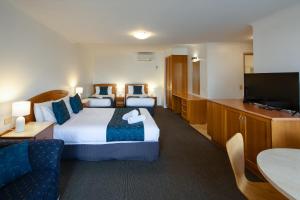 a hotel room with two beds and a flat screen tv at Waves on Banyan formerly Comfort Inn International in Warrnambool