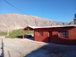 a red building with a mountain in the background at Maimara Hospedaje Sumalawa in Maimará +1 photo