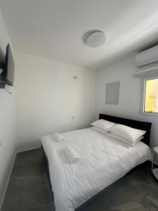 a bedroom with a white bed with white sheets and pillows at Beachfront Haven - Perfect for Groups in Ashdod