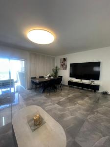 a living room with a table and a flat screen tv at Beachfront Haven - Perfect for Groups in Ashdod