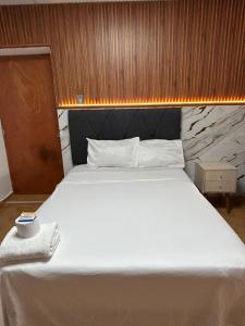 a bedroom with a large white bed with a wooden wall at Hostal La Huerta in Huánuco