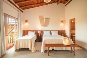 a bedroom with two beds and a table at Falésias Orybá in Corumbau +27 photos