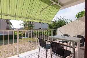 a patio with a table and chairs on a balcony at Apartment Polugic in Punat