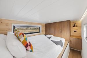 a large bed in a small room with a window at Ginger GOAT - Luxury New Tiny Home in Jindabyne