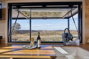 a kitchen with a window with a bottle of wine on a counter at Ginger GOAT - Luxury New Tiny Home in Jindabyne