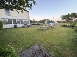 a yard with two picnic tables in front of a building at Taldrwst At Dwyran in Dwyran