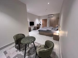 a bedroom with a bed and two chairs and a table at الباحه للشقق المخدومه in Al Baha