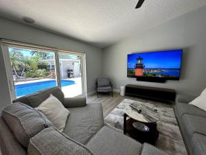 a living room with a couch and a flat screen tv at Jupiter Heated Pool/Spa Luxury 3Bed Home in Jupiter