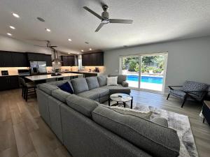 a living room with a gray couch and a kitchen at Jupiter Heated Pool/Spa Luxury 3Bed Home in Jupiter
