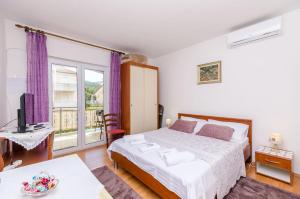 a bedroom with a bed and a television and a balcony at Apartments Emmas studio in Stari Grad