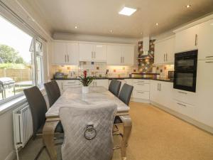 a kitchen with a table and chairs and a kitchen with white cabinets at 59 Nursery Avenue in Coleraine