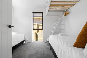 a bedroom with two beds and a ladder next to a window at Roam Taupo Upper Terrace Unit 3 - Spa Pool in Taupo
