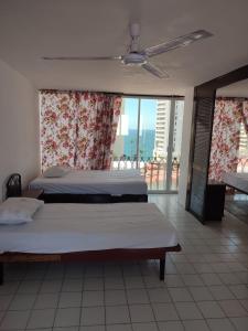 a bedroom with two beds and a large window at Hotel Condesa Americana Acapulco in Acapulco