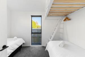 two beds in a room with a ladder and a window at Roam Taupo Lake Front Unit 2 - Spa Pool in Taupo