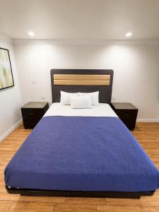 a bedroom with a large bed with a blue blanket at BELL RESORT MOTEL in Bell +4 photos