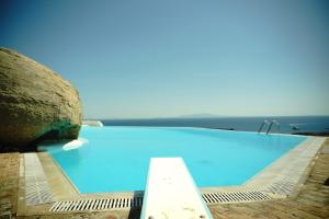 a large blue swimming pool with the ocean in the background at Orama Suite II Mykonos Sunset & Pool in Mikonos