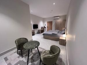 a bedroom with a bed and two chairs and a table at الباحه للشقق المخدومه in Al Baha