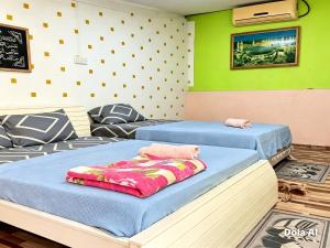 two beds in a room with green walls at Dahlia Roomstay Jelai in Gemas