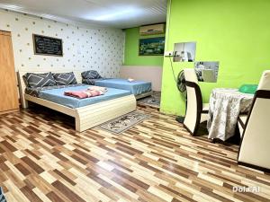 a room with a bed and a table and green walls at Dahlia Roomstay Jelai in Gemas +2 photos