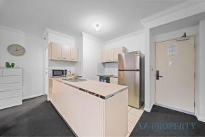 a kitchen with white cabinets and a stainless steel refrigerator at Perth CBD Hideaway Walk to Everything in Perth