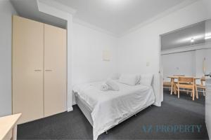 a white bedroom with a bed and a table at Perth CBD Hideaway Walk to Everything in Perth