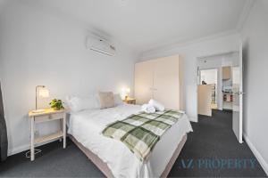 a white bedroom with a bed and a night stand at Perth CBD Hideaway Walk to Everything in Perth