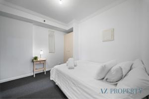 a white bedroom with a bed and a table at Perth CBD Hideaway Walk to Everything in Perth +41 photos