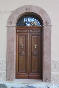 a wooden door with an arch in a building at Porta Baciamano in Geraci Siculo